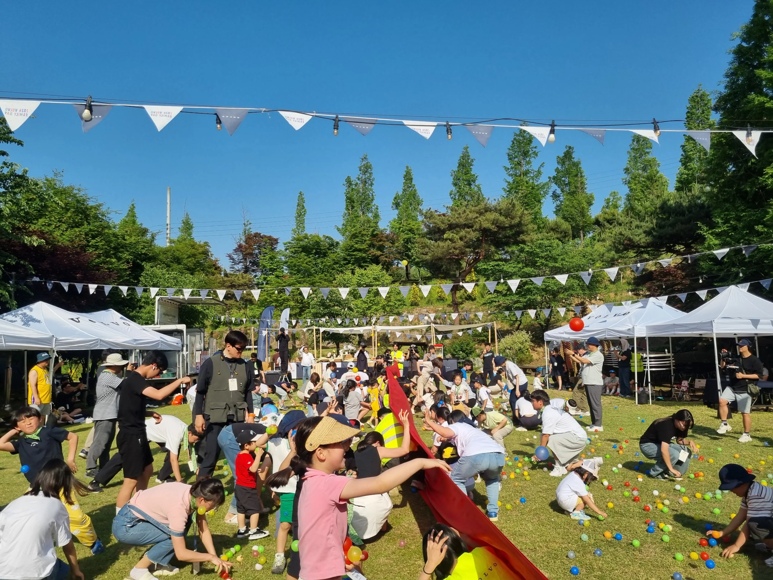 야외 행사장에 조명 장식 아래 멀리 모여 있는 참가자들