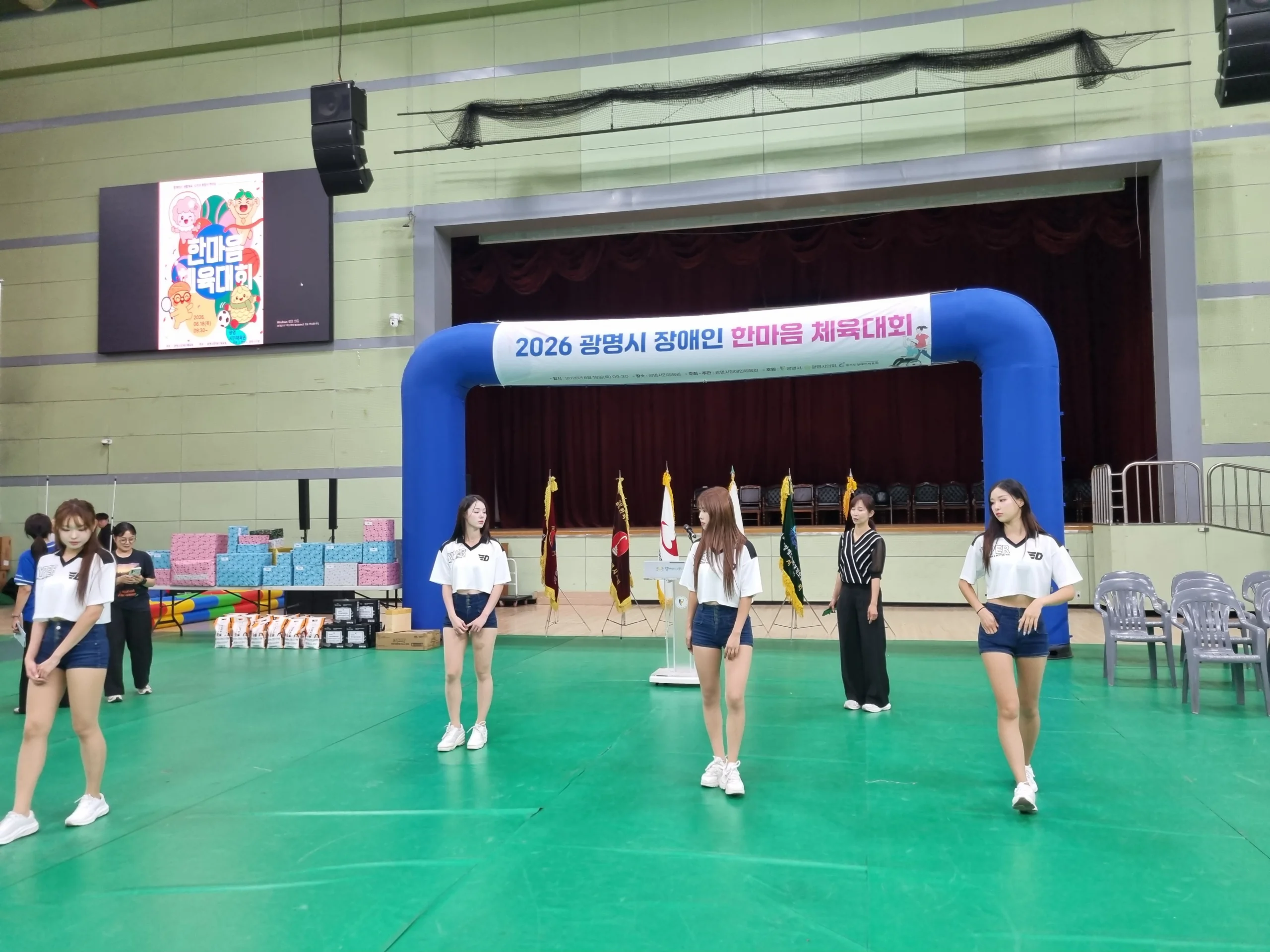 체육관에서 에어 아치를 배경으로 치어리더가 공연하고 관중이 지켜보는 모습